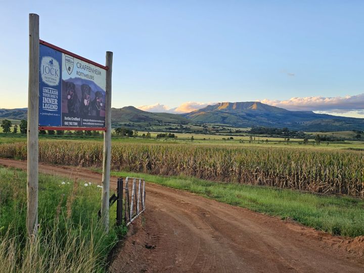 The farm gate and Craffenheim Rottweilers sign on the road in, with maize fields and mountains beyond